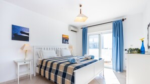 Une chambre à coucher avec un lit, des tables de chevet, une commode et une vue sur l’extérieur.