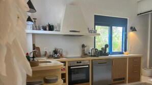 Ett modernt kök med en inbyggd ugn, diskmaskin och ett fönster med utsikt över grönområden.