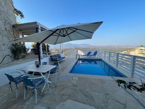 A pool area with a view of the mountains, stone flooring, and outdoor seating. - Luxury apartment in Crete with private pool, sea and mountain views. (Kamilári)