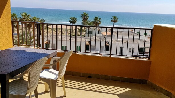 Een balkon met uitzicht op strand en zee.