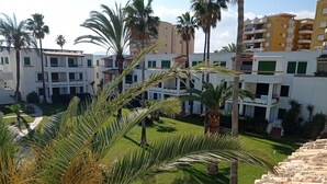 Zona residencial con edificios de varios pisos, palmeras y un césped bien cuidado.