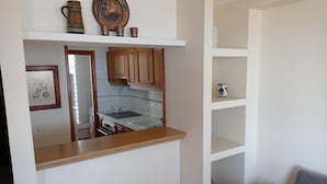 Una cocina compacta con armarios de madera, una encimera blanca y un horno empotrado.