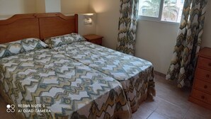 Une chambre à coucher avec un lit, une table de chevet et une fenêtre avec des rideaux.