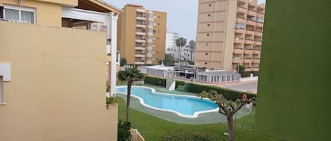 A residential area with a swimming pool, green lawns, and multi-story buildings.