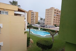 Zona residencial con piscina, césped verde y edificios de varios pisos.