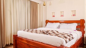 A neatly made bed with a wooden headboard, white bedding, and a patterned blanket. - PORI CITY HOTEL (Nairobi)
