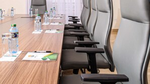 A conference room with a long table, black chairs, water bottles, and documents. - PORI CITY HOTEL (Nairobi)