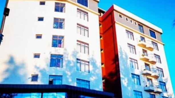 A hotel with a modern design, featuring a prominent corner building with a glass facade and a smaller attached structure. - PORI CITY HOTEL (Nairobi)