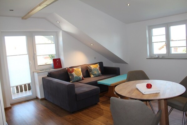 A modern living room with a sofa, a coffee table, and a dining table.