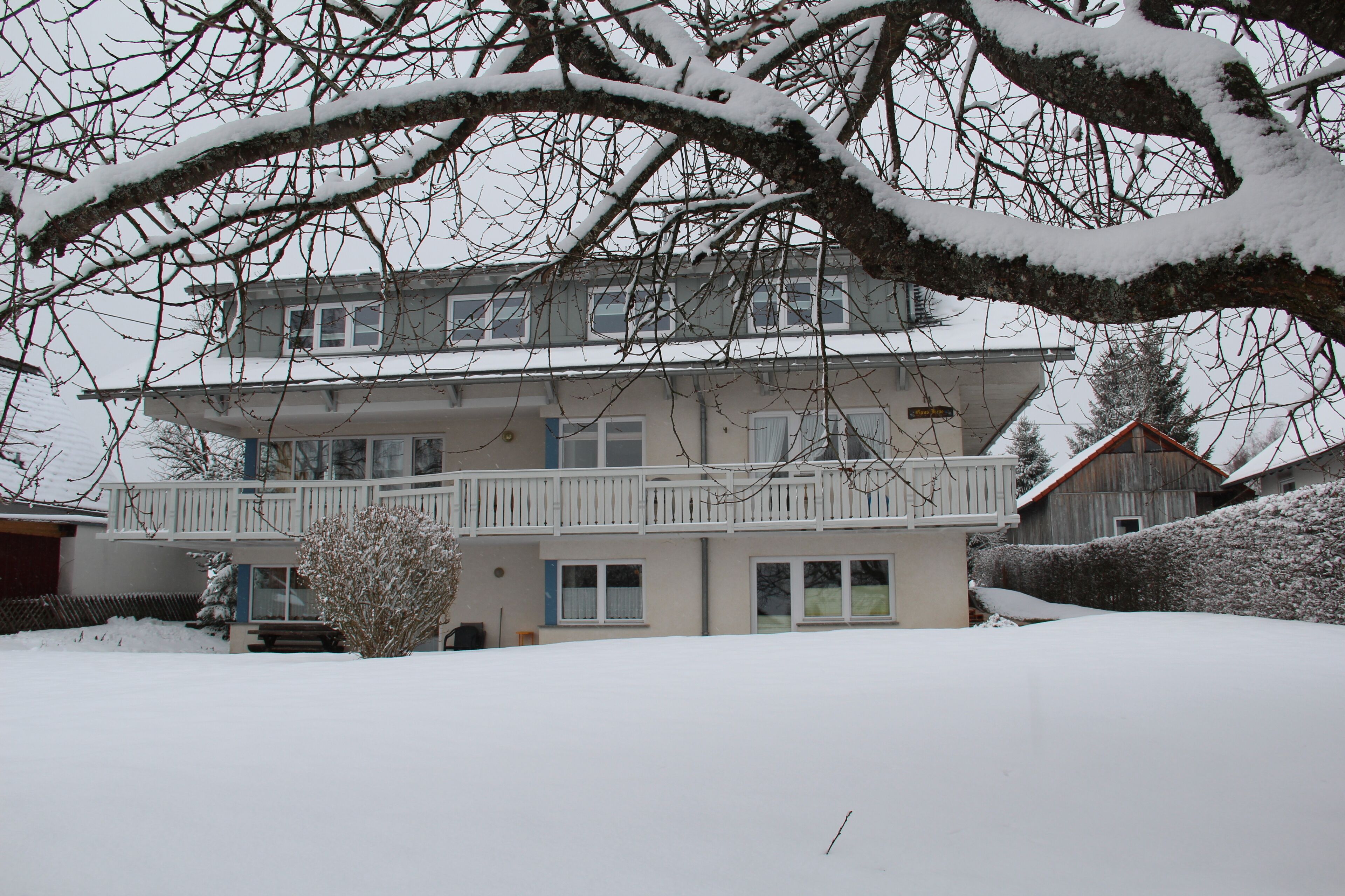 Un edificio de dos pisos con un balcón, rodeado de nieve.