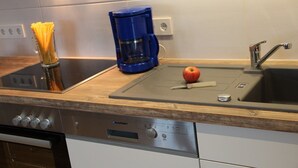 Eine Küche mit Herd, Kaffeemaschine und Spüle inklusive Wasserhahn.