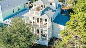 A multi-story house with a balcony, a covered porch, and a small garden area.