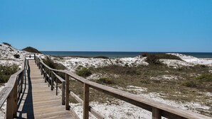 A wooden boardwalk leading to a beach with dunes and the ocean in the background.