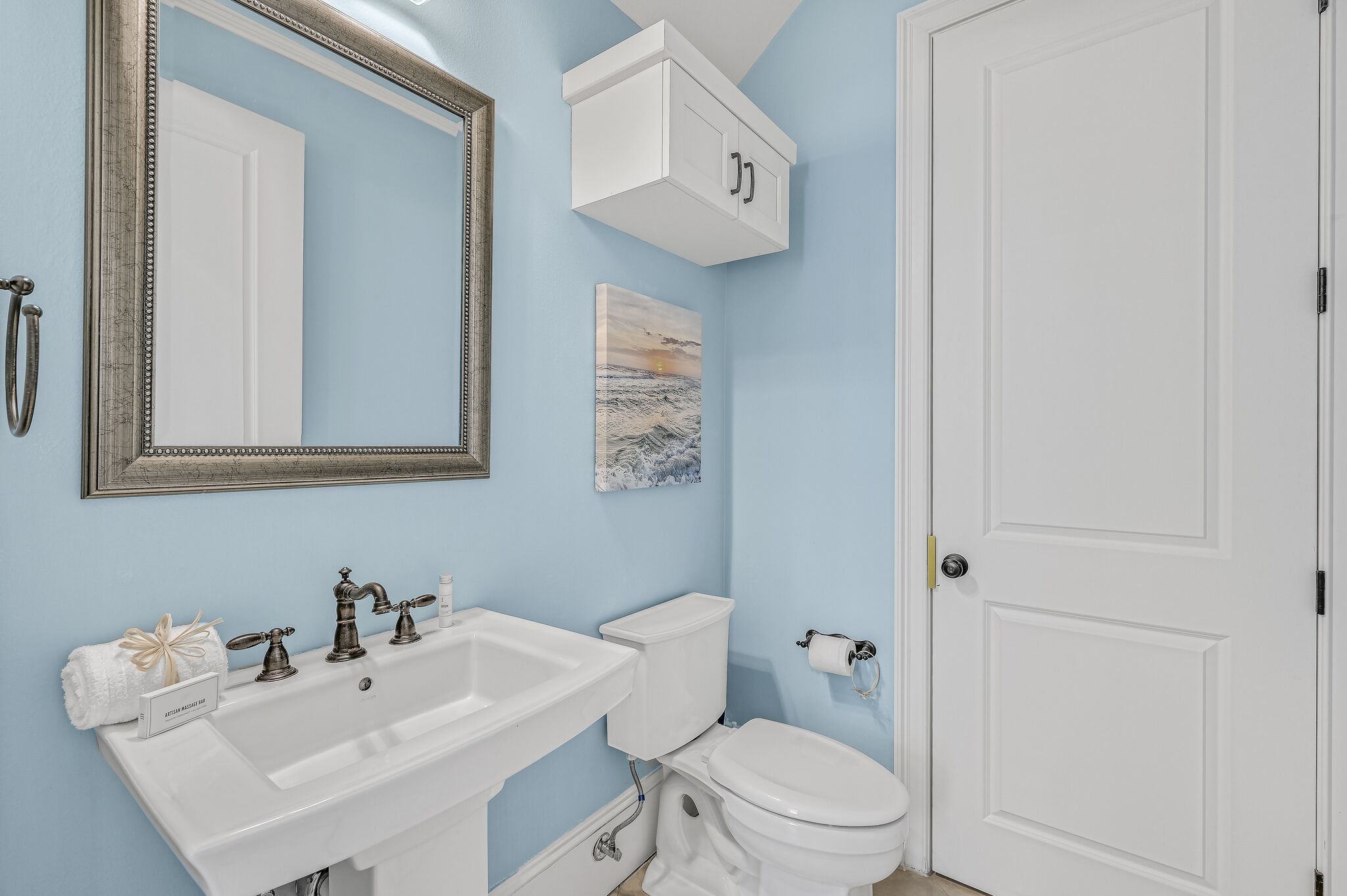A bathroom with a white sink, a toilet, a mirror, and a cabinet.