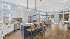 A spacious kitchen with a large island, white cabinetry, and a wooden floor.