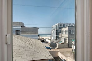 A residential area with a view of the beach, houses with balconies, and a clear sky.