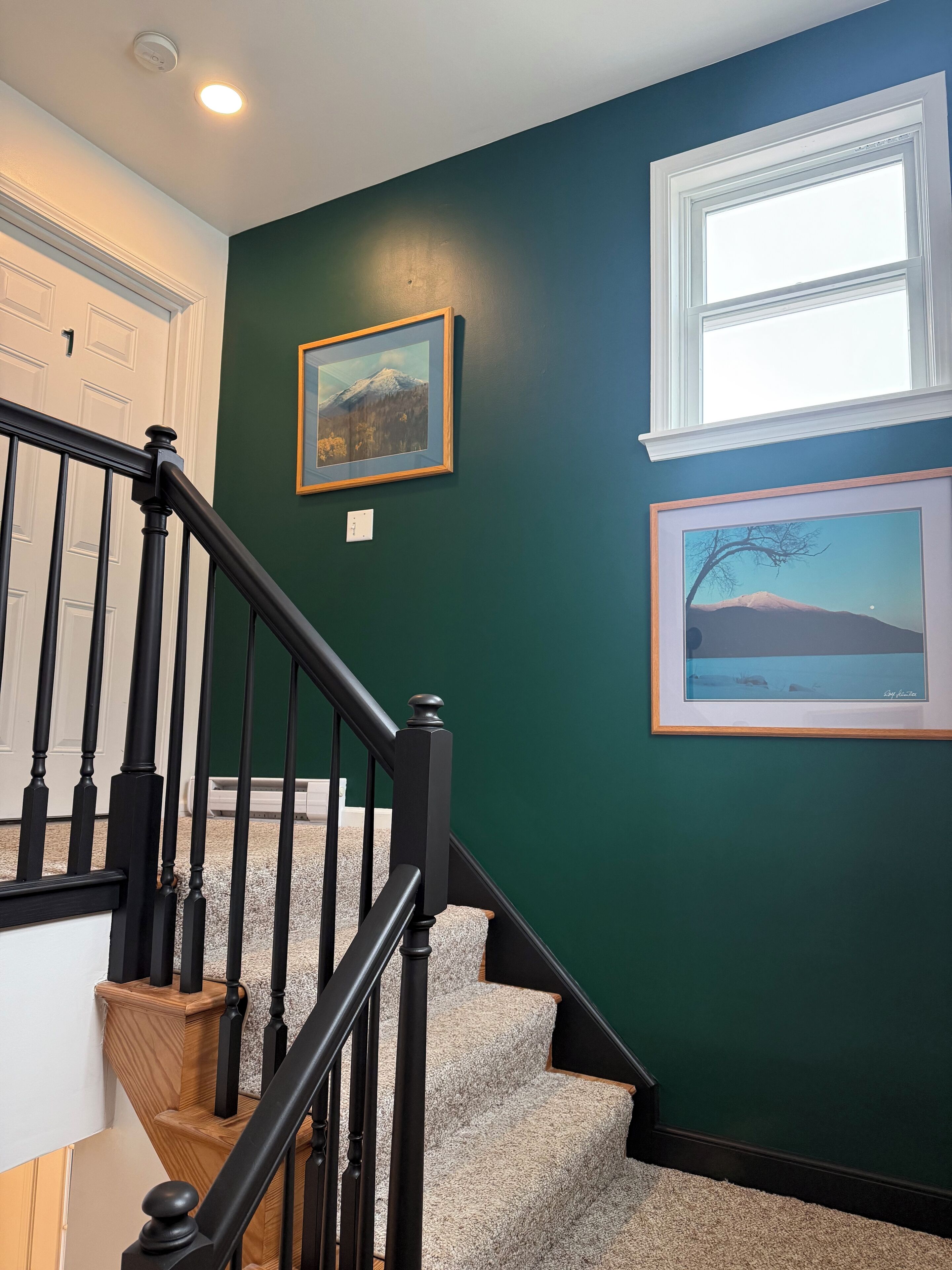 A staircase with black railings and wooden steps leading to a landing.