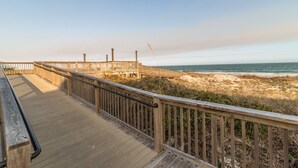 A wooden boardwalk leading to a beach with a clear view of the ocean.