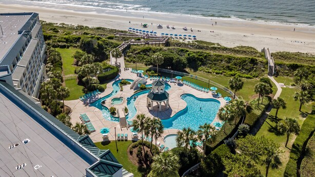 A resort with a large swimming pool, beach access, and a view of the ocean.