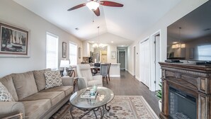A spacious living room with a large sofa, a coffee table, and a fireplace. There is a dining area with a table and chairs, and a kitchen in the background. - TB 12H  Bedroom/Three Bath unit in True Blue (Pawleys Island)
