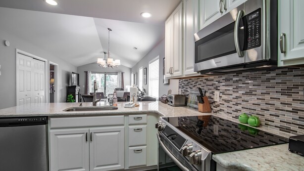 A modern kitchen with white cabinets, stainless steel appliances, and a patterned backsplash. - TB 12H  Bedroom/Three Bath unit in True Blue (Pawleys Island)