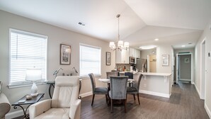 A spacious living room with a dining area, a kitchen in the background, and a hallway leading to other rooms. - TB 12H  Bedroom/Three Bath unit in True Blue (Pawleys Island)