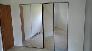 A room with a wooden door, a white wall, and a mirrored wardrobe with three doors. - Single family home+ large rooms +kitchen + living room+den roo + beautiful  yard (Catonsville)