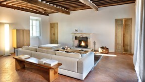 A cozy living room with a fireplace, wooden beams, a sofa, and a coffee table. - VILLA CARNICELLI eco-friendly,sustainable, 450m² (4,850ft²),private pool, design (Gragnano di Capannori)