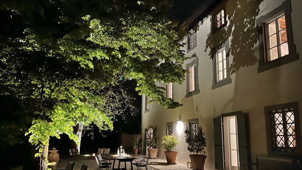 An outdoor patio area with a table and chairs, potted plants, and a large tree providing shade. - VILLA CARNICELLI eco-friendly,sustainable, 450m² (4,850ft²),private pool, design (Gragnano di Capannori)