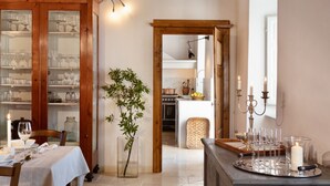 A dining area with a wooden cabinet filled with glassware, a dining table set with plates and glasses, and a vase with a plant. - VILLA CARNICELLI eco-friendly,sustainable, 450m² (4,850ft²),private pool, design (Gragnano di Capannori)