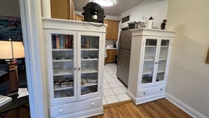 Una cocina con armarios blancos, un refrigerador y un microondas.