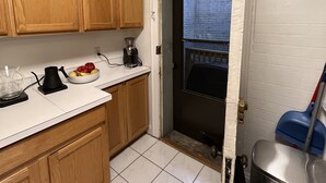 Una cocina con armarios de madera, una encimera con cafetera, un bol de fruta y vistas a un balcón.