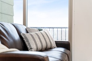 Un canapé en cuir, agrémenté d’un coussin à carreaux, donnant sur un balcon avec une balustrade.