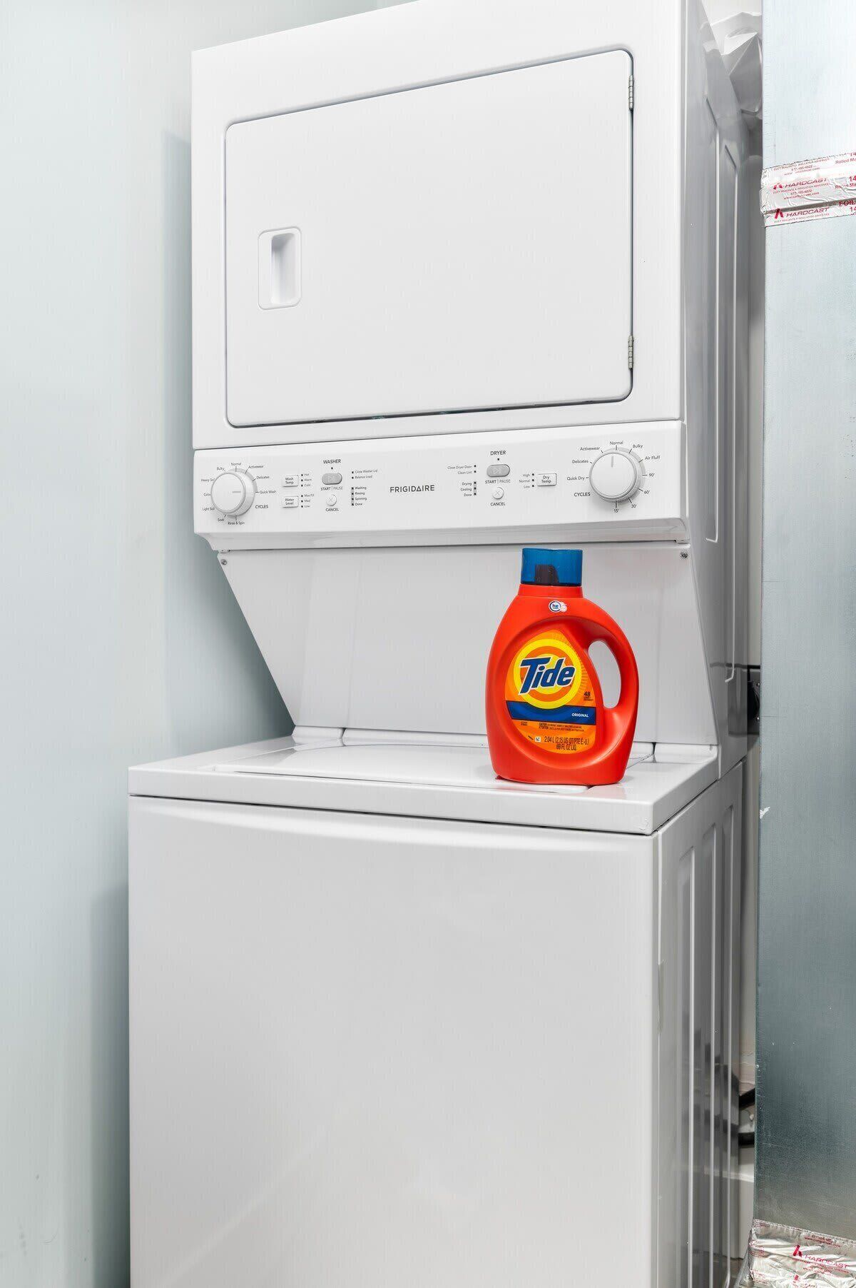 A white washing machine with a Tide detergent bottle on top.