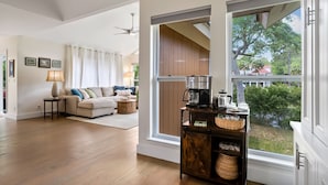 A spacious living room with a large window, a sofa, a coffee table, and a wooden cabinet with baskets. - **The Caddy's Shack** 1 story home with Club Cards Optional (Fripp Island)