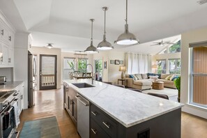 Een moderne keuken met een groot kookeiland, inbouwapparatuur en hanglampen.