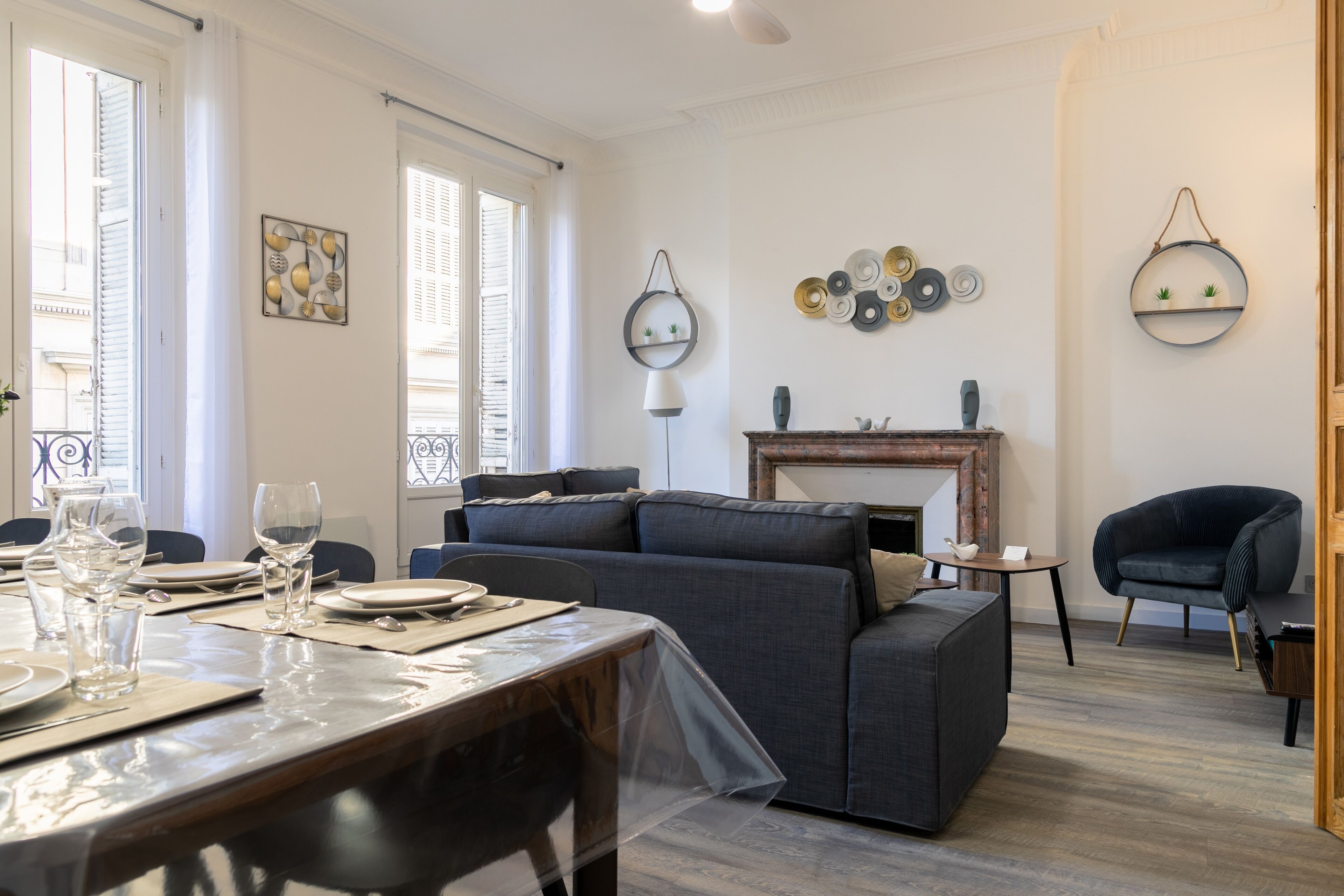 Een moderne woonkamer met een bank, een eettafel gedekt voor twee personen en een open haard.