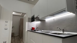 Cocina moderna con armarios blancos, encimera negra y pileta de acero inoxidable.