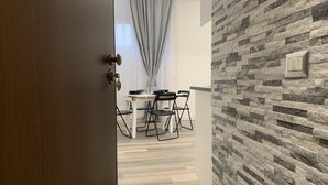 Un comedor moderno con una mesa, sillas, un muro de piedra decorativa y un interruptor de luz a la vista.