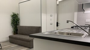 Una cocina moderna con un lavamanos integrado, un sofá gris y una planta de bambú.