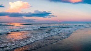Una playa con olas y un atardecer.