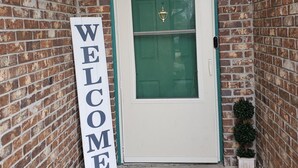 A brick wall, a green door, a welcome sign, and a welcome mat. - Cozy 3 bedroom house (Indianapolis)