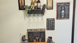 A bar area with a wooden table, wine bottles, glasses, and a chalkboard sign advertising a happy hour. - Cozy 3 bedroom house (Indianapolis)