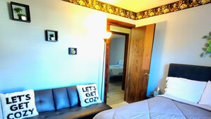 A bedroom with a bed, a sofa, and a wall with a decorative border. - Cozy 3 bedroom house (Indianapolis)
