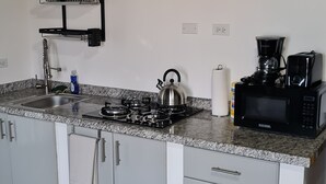 Una cocina con encimera de granito, electrodomésticos de acero inoxidable, un hervidor, una cafetera y un escurreplatos.