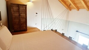 Un dormitorio con techo de madera, una cama, un armario y una lámpara colgante.