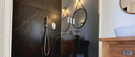 A modern bathroom with a glass-enclosed shower, a wooden vanity, and a mirror.