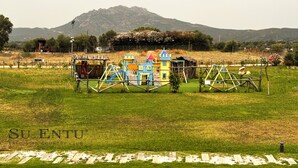 A playground with colorful play structures in a grassy field with a mountain in the background. - Su Entu Boutique Hotel (Olbia)