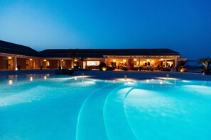Een hotel met een groot zwembad, een terras voor buiten eten en meerdere gastenkamers.