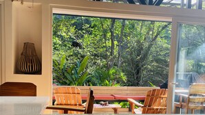 A kitchen with a large window overlooking a lush garden. There is a wooden table and chairs, and a vase on the wall. - SAMARA - Stunning 2 bedroom House 15 min from the Beach. (Sámara)